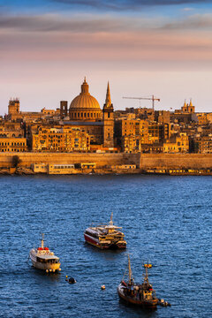 Malta, Valletta, City skyline at sunset, boats in Marsamxett Harbour in foreground