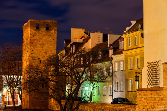 Ccity wall tower and traditional houses at night, Warsaw, Poland