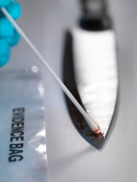 Forensic scientist taking DNA evidence from a blood smeared knife