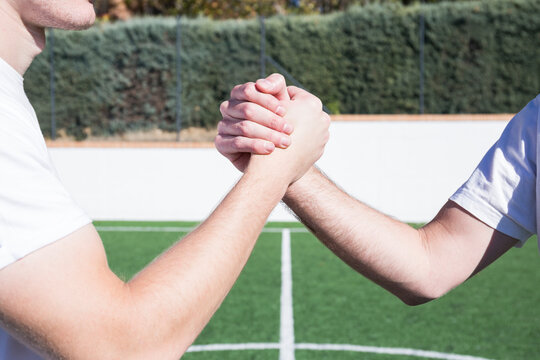 Close-up of two football players shaking hands on football field