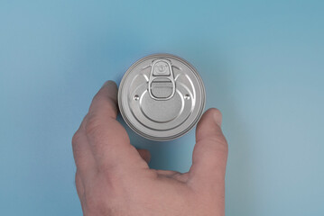 The hand takes a tin can. On a blue background. Close-up