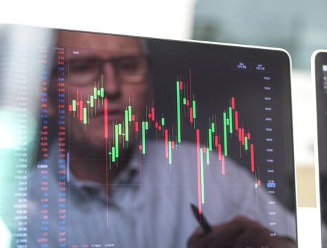 Reflection of a stock trader viewing the performance of a company share price on screen