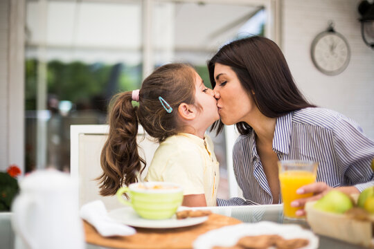 Mother and daughter kissing during breakfast at home