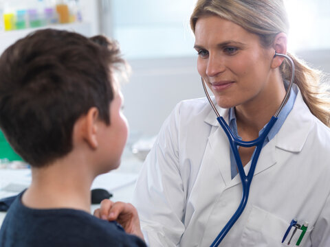 Female Doctor Listening To A Boys Heart Beat Using A Stethoscope During A Health Check In A Clinic