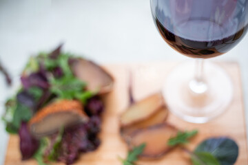 Background blurred salad vegetables and balyk with a glass of wine