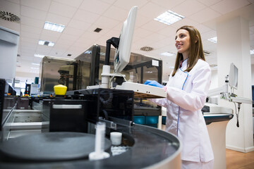 Young woman in white apparel using sample analyzer while working in research lab
