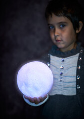 Naklejka premium Cute little girl holds the tiny shiny Moon