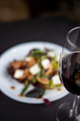 Background blurred salad vegetables and balyk with a glass of wine