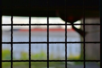 Metal grate in window opening on blurred colored background