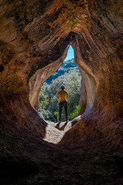 Young man standing in cave entrance, Cova Simanya,Barcelona, Spain