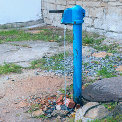 old outdoor water pump in the yard by a stone wall