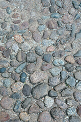 a fragment of a section of a country road made of stones of different sizes and shapes in the ancient Russian city of Pskov, Russia