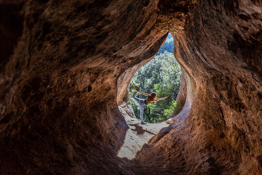 Young woman practising yoga in cave entrance, Cova Simanya,Barcelona, Spain
