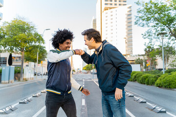 Two happy friends fist bumping in the city, Barcelona, Spain
