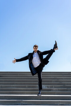 Businessman standing on on leg on stairs