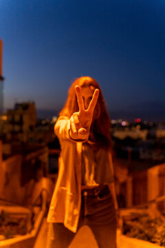 Young woman doing peace sign at blue hour
