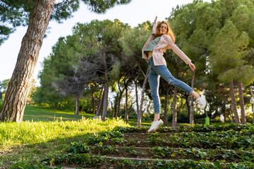 Young redheaded woman jumping on steps in a park