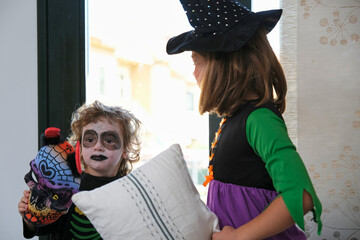 Little boy with painted face in Halloween costume. Holding a mask in his hand.