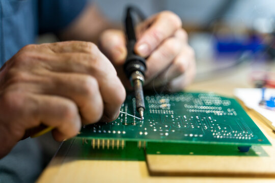 Senior man working on electronic circuits in his workshop, close up