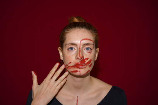 Portrait of young woman smearing paint on her face