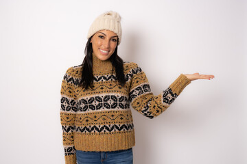 Smiling woman in winter clothing showing product with hand isolated over white background.