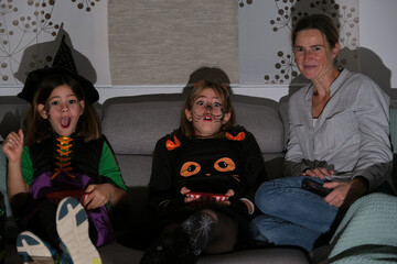 Mother with her daughters watching a horror movie on halloween