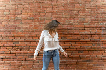 Portrait of youngwoman in front of a brick wall, shaking her head