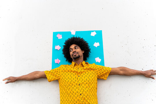 Young man wearing yellow shirt, blue indicating label with arrow signs