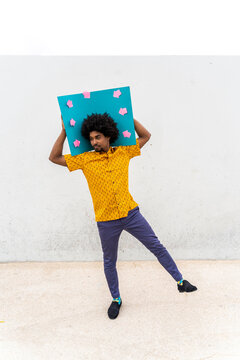 Young man wearing yellow shirt, blue indicating label with arrow signs
