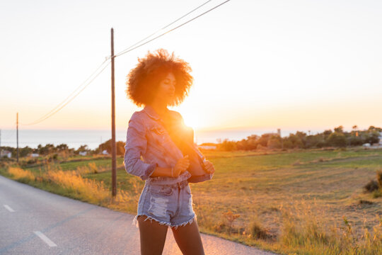 Young woman standing on street with closed eyes at sunset, Ibiza