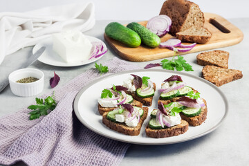 Canapés with toasted bread with sunflower and flax seeds, feta cheese, cucumber and onion