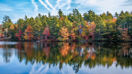  Autumn foliage colors reflect into the still waters of a lake in rural Nova Scotia on an early sunny day in autumn.