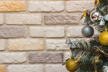 Mockup with decorated Christmas tree. Composition with gold and silver baubles, bows, animals, bells, lit garlands. Copy-space on the decorative brick wall background. Close-up, selective focus