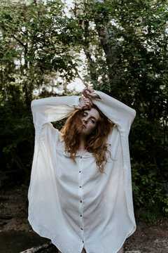 Young redhaired woman wearing baggy shirt in forest