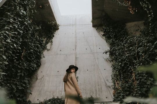 Young woman in underground tunnel, concrete wall full of plants