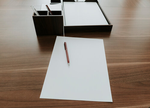 Ballpen and paper on wooden desk in office