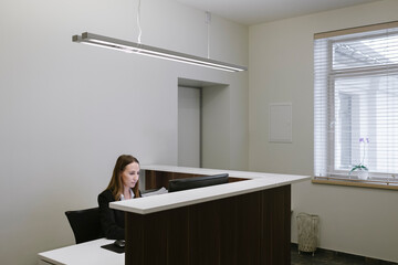Young woman working at the reception desk in office