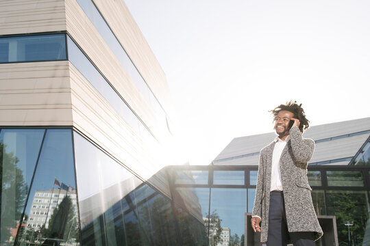Smiling businessman talking on cell phone outside office