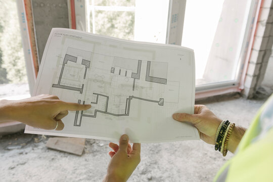 Two architects pointing a architectural plan at construction site