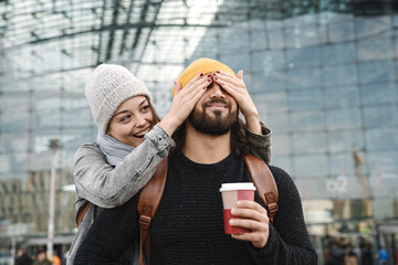 Happy young woman surprising boyfriend at the central station, Berlin, Germany