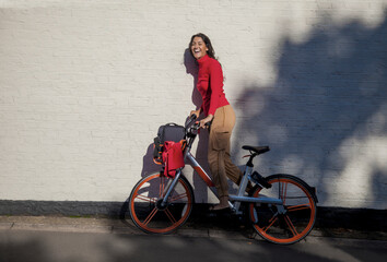 Carefree young woman riding a rental bike