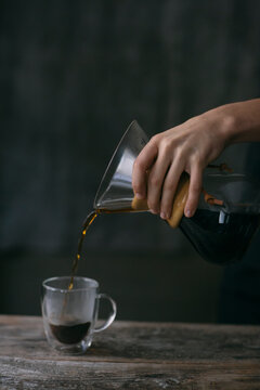 Close-up of man pouring filtered coffee into a glass