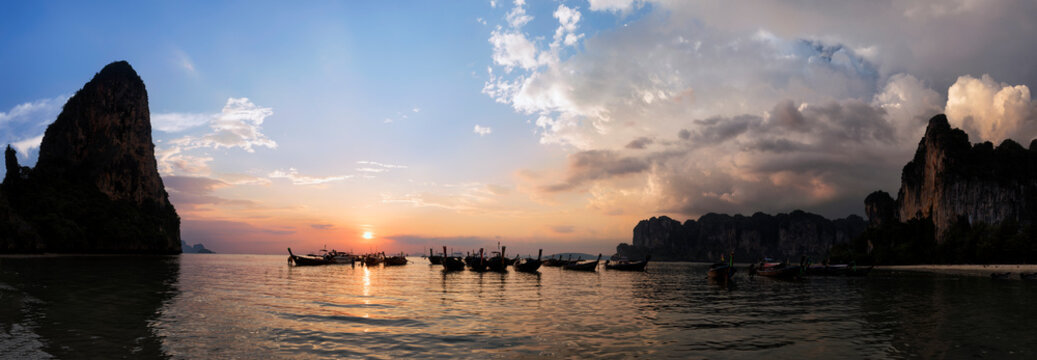 Thailand, Krabi, Railay beach, bay with long-tail boats floating on water at sunset