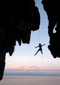 Thailand, Krabi, Lao Liang island, climber abseiling from rock wall above the sea