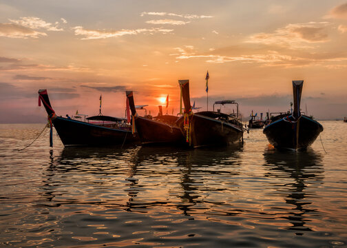 Thailand, Krabi, Railay beach, long-tail boats floating on water at sunset