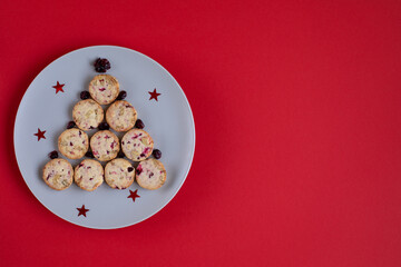 Cute edible Christmas tree made of cookies on a round plate on a red background. Creative tree. Concept holidays, pastries, New Year.