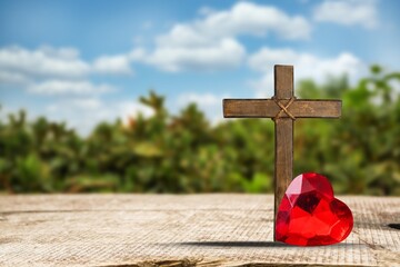 Red heart with a wooden Christian cross on floor in the morning light,