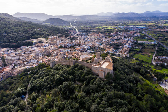 Aerial view of Castle Of Capdepera by trees in village against sky