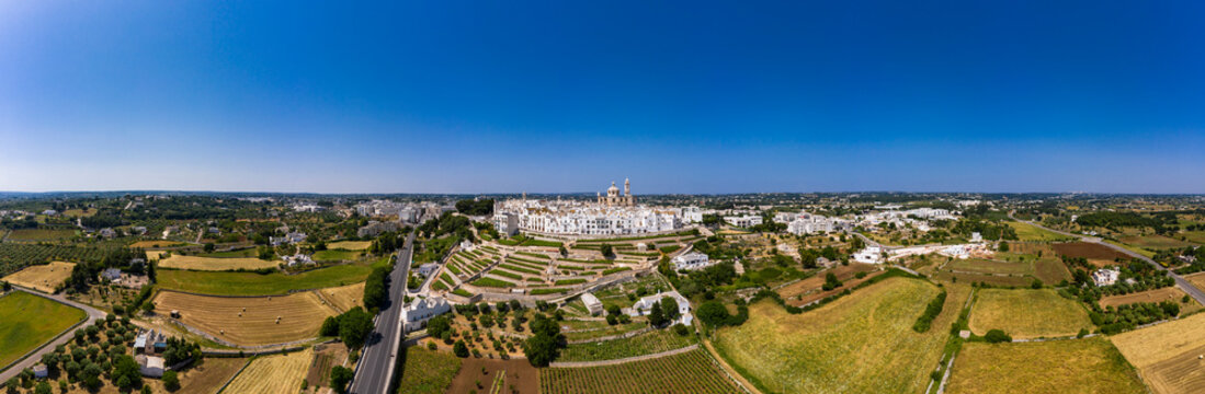 Italy, Locorotondo, Aerial panorama of clear blue sky over fields and vineyards with town in background