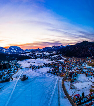 Germany, Bavaria,&Ocirc;&oslash;&Omega;Reit&Ocirc;&oslash;&Omega;im&Ocirc;&oslash;&Omega;Winkl, Helicopter view of&Ocirc;&oslash;&Omega;snow-covered&Ocirc;&oslash;&Omega;mountain village at dawn